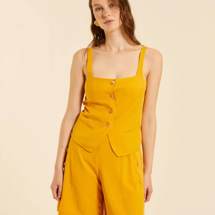 Chaleco amarillo de tirantes con escote cuadrado y botones decorativos frontales.
