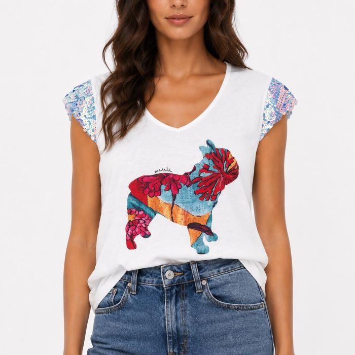 Modelo con camiseta Princesa de Malala blanca con estampado de perro y mangas de lentejuelas combinada con vaqueros y sandalias rojas.