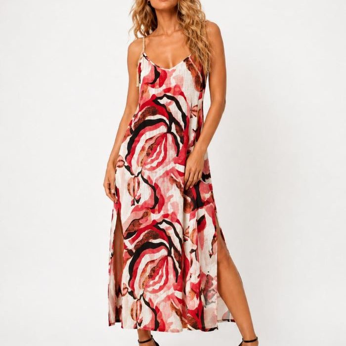 Modelo rubia con vestido Malala Sensibilidad largo estampado en tonos rojos y rosas, tirantes decorativos y sandalias negras de tacón sobre fondo blanco.